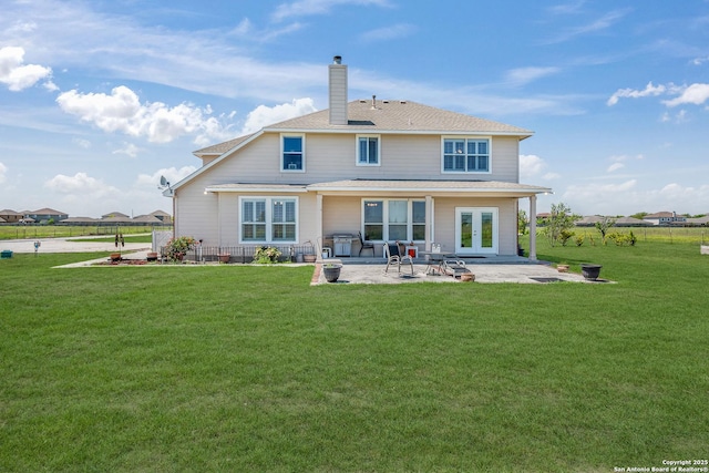 rear view of house featuring a lawn, a patio area, and french doors