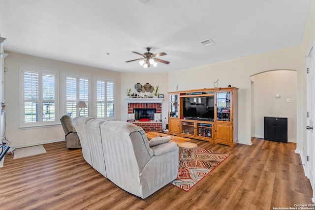 living room with a fireplace, wood-type flooring, and ceiling fan