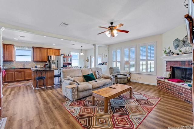 living room featuring dark hardwood / wood-style floors, a wealth of natural light, and a brick fireplace