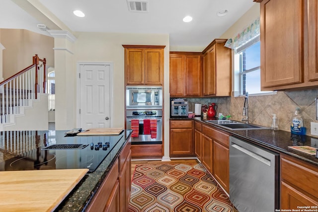 kitchen featuring ornate columns, sink, backsplash, dark stone countertops, and appliances with stainless steel finishes