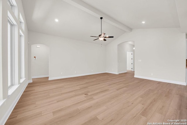 unfurnished room featuring arched walkways, ceiling fan, lofted ceiling with beams, baseboards, and light wood-type flooring