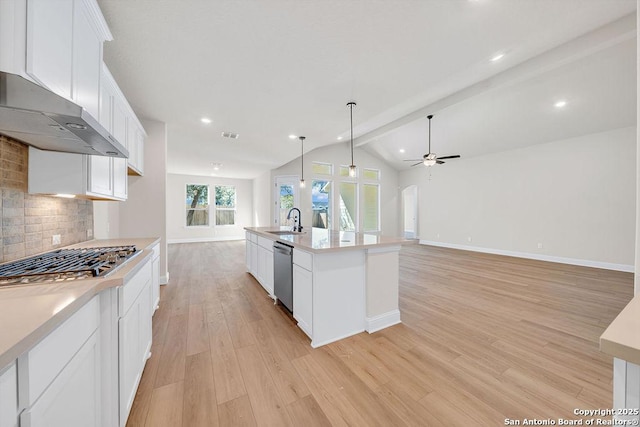 kitchen with a center island with sink, lofted ceiling with beams, appliances with stainless steel finishes, light countertops, and white cabinetry