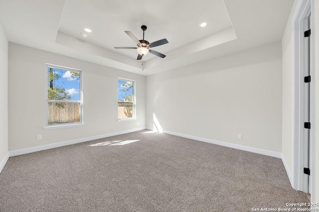 carpeted spare room featuring a tray ceiling, baseboards, and recessed lighting