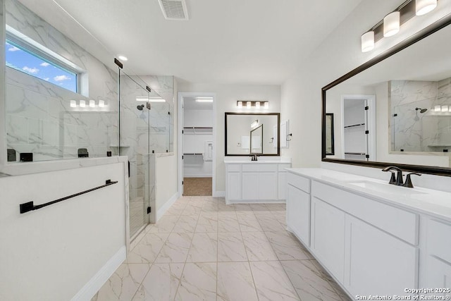 full bath featuring a stall shower, visible vents, marble finish floor, a walk in closet, and a sink