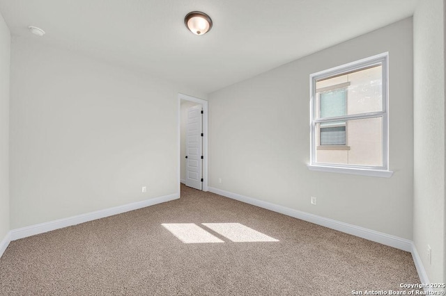 spare room featuring carpet and baseboards