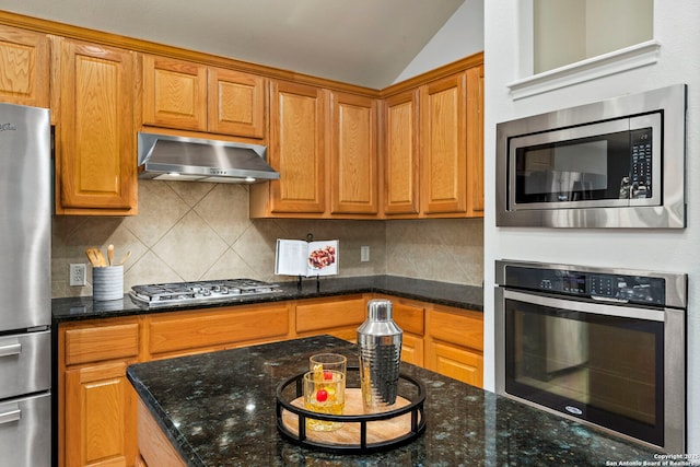 kitchen with stainless steel appliances, vaulted ceiling, tasteful backsplash, and dark stone countertops