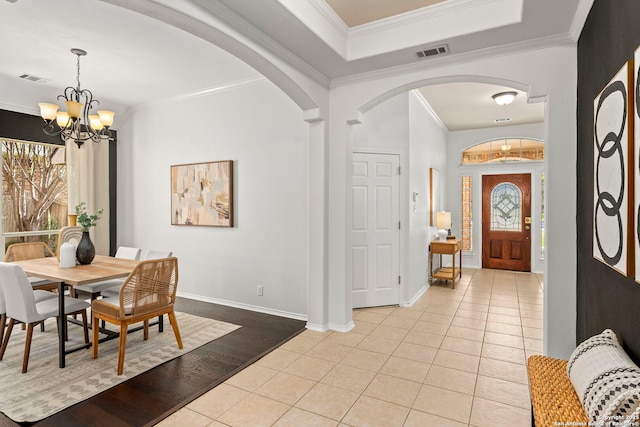 foyer featuring light tile patterned floors, ornamental molding, and a chandelier