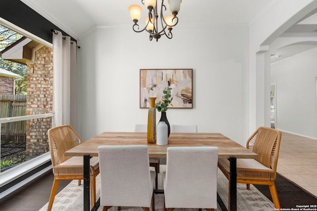 tiled dining space featuring ornamental molding, vaulted ceiling, and an inviting chandelier