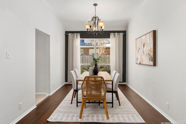 dining space featuring dark hardwood / wood-style floors, an inviting chandelier, and ornamental molding