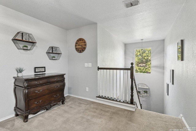 hall with light carpet and a textured ceiling