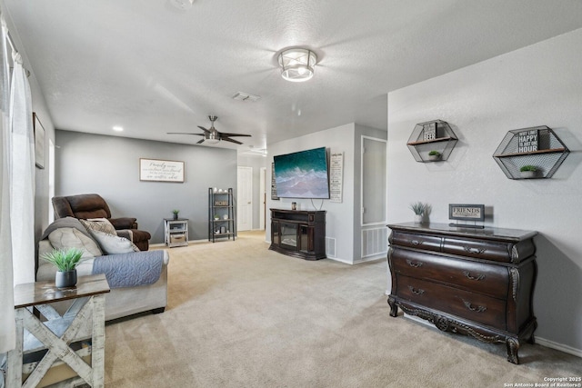 carpeted living room with ceiling fan and a textured ceiling