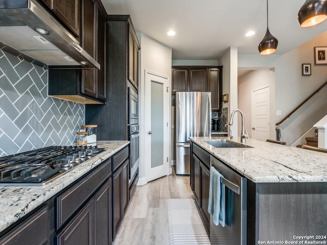 kitchen featuring appliances with stainless steel finishes, tasteful backsplash, extractor fan, sink, and hanging light fixtures