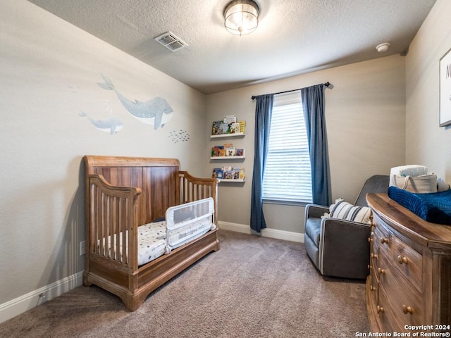 carpeted bedroom with a crib and a textured ceiling