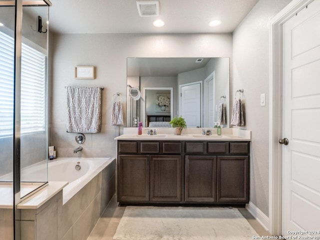 bathroom with vanity, tiled bath, and a wealth of natural light