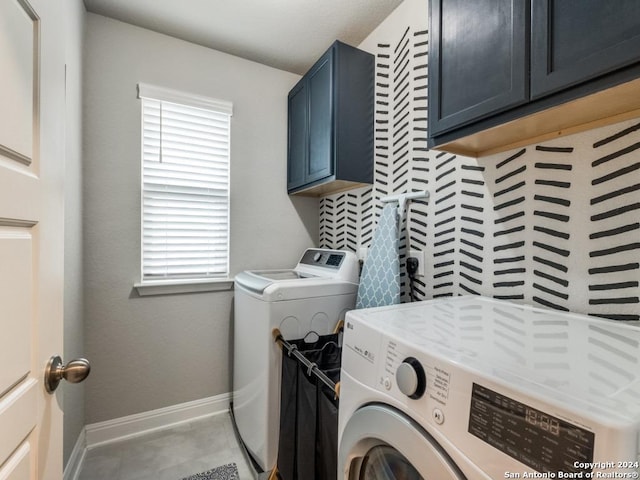 clothes washing area with washer and dryer, a wealth of natural light, and cabinets