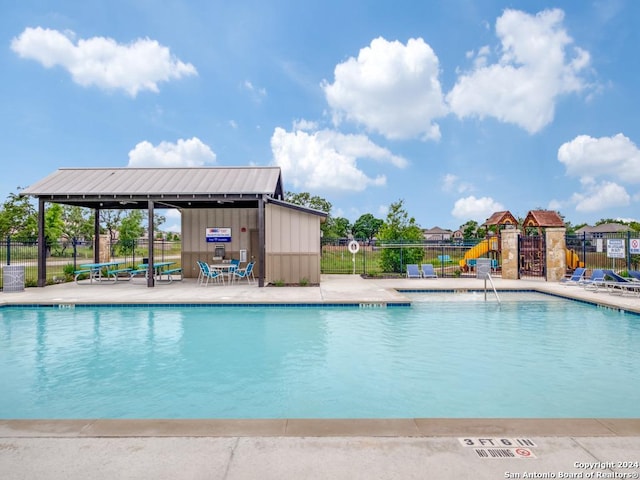 view of pool with a playground and a patio area