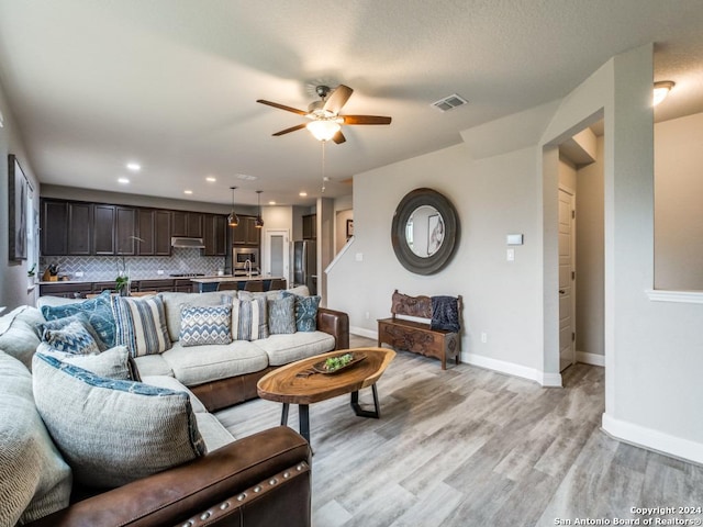 living room with ceiling fan and light wood-type flooring