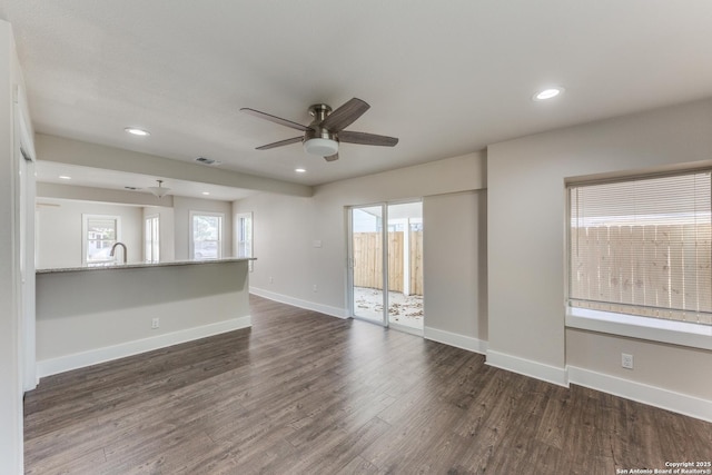 unfurnished living room with ceiling fan, dark wood-type flooring, and sink