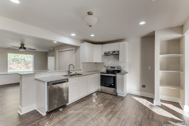 kitchen with white cabinetry, sink, stainless steel appliances, light stone counters, and kitchen peninsula