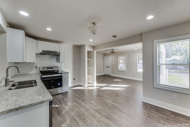 kitchen featuring backsplash, light stone counters, sink, electric range, and white cabinetry