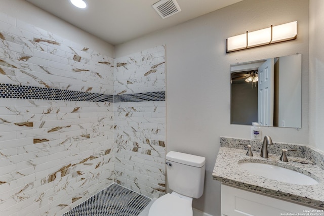 bathroom with tiled shower, vanity, and toilet