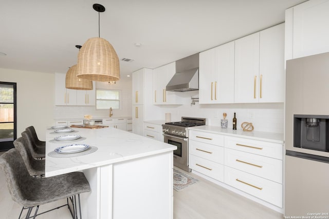 kitchen with white cabinets, white refrigerator with ice dispenser, high end stainless steel range, and wall chimney range hood