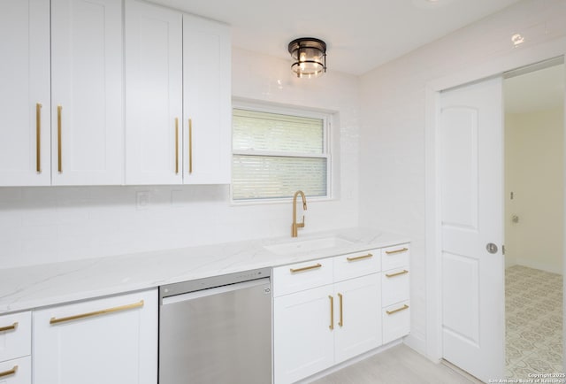 kitchen featuring stainless steel dishwasher, white cabinets, and light stone countertops