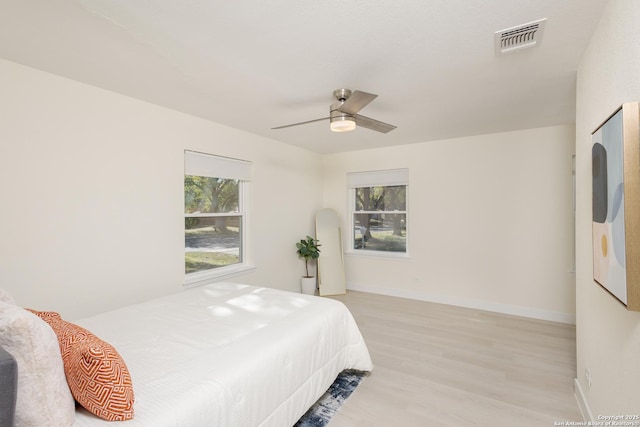 bedroom with ceiling fan, multiple windows, and light hardwood / wood-style flooring