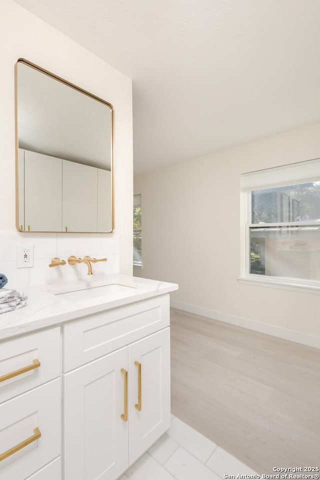 bathroom featuring tile patterned floors, vanity, a healthy amount of sunlight, and backsplash