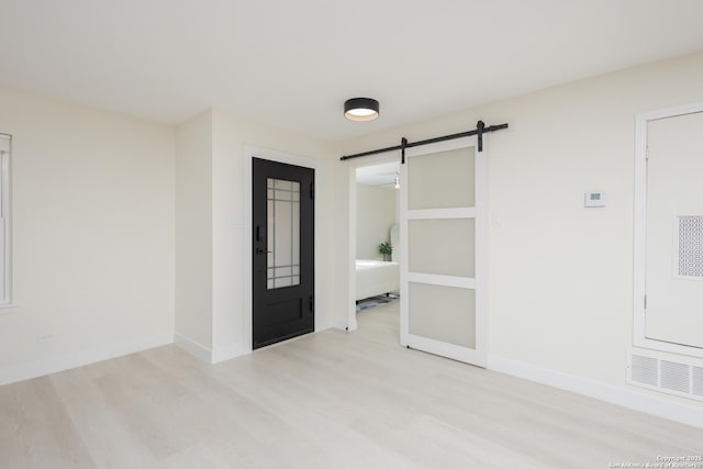 empty room with a barn door and light wood-type flooring