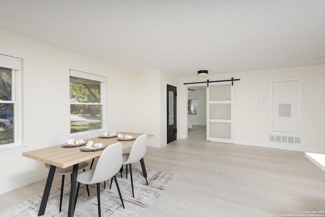 dining area with a barn door and light hardwood / wood-style floors