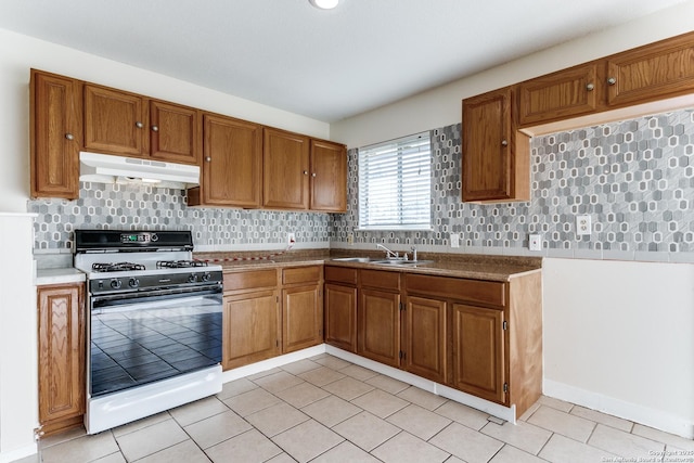 kitchen featuring tasteful backsplash, sink, light tile patterned floors, and white stove