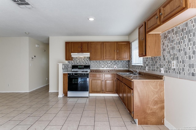 kitchen with decorative backsplash, white range with gas stovetop, sink, and light tile patterned floors