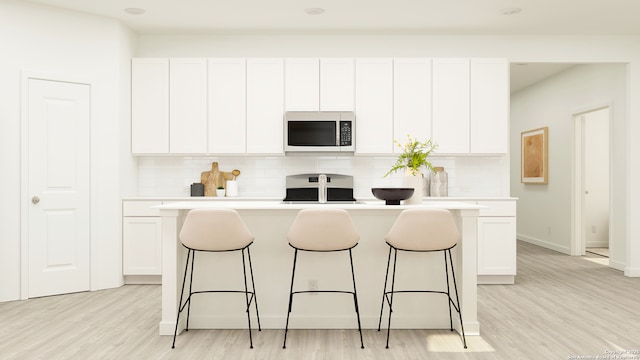 kitchen featuring a center island with sink, white cabinets, and stove