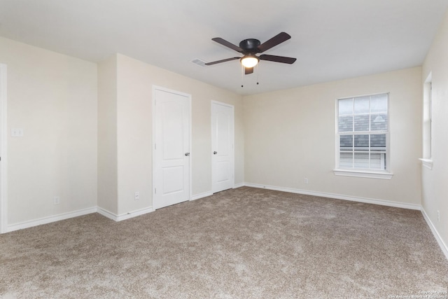 unfurnished bedroom with carpet flooring, ceiling fan, and two closets