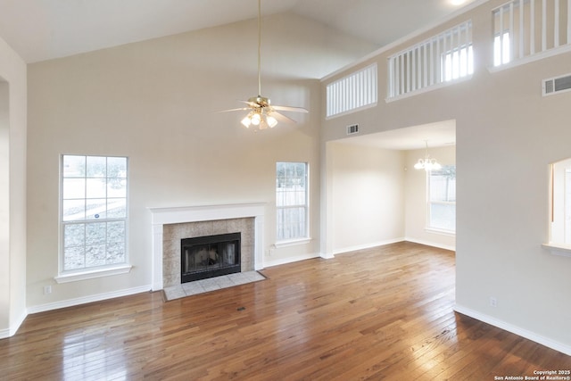 unfurnished living room with ceiling fan with notable chandelier, hardwood / wood-style flooring, and high vaulted ceiling