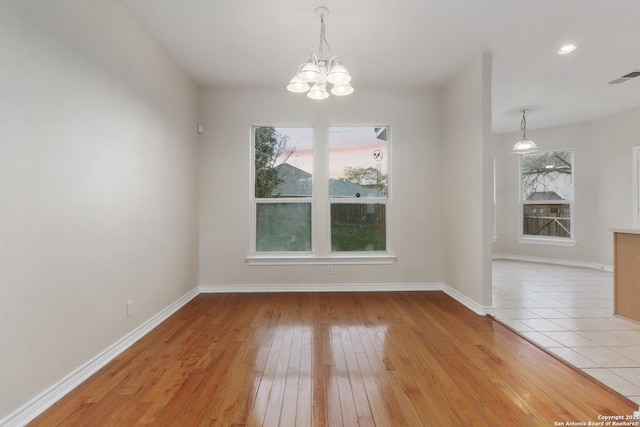 unfurnished dining area with a healthy amount of sunlight, light wood-type flooring, and a chandelier