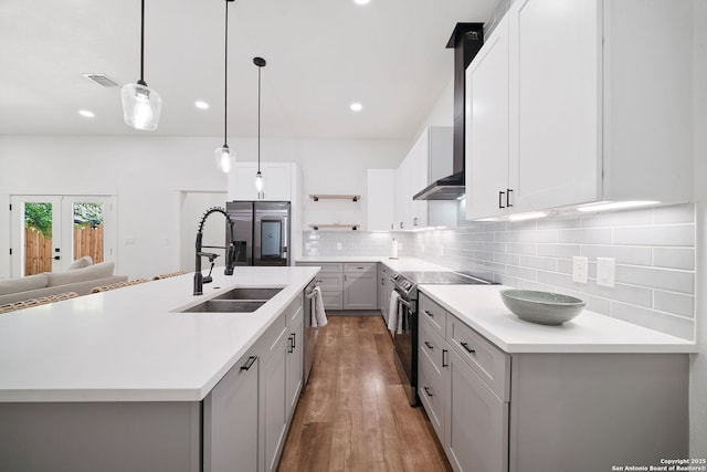 kitchen featuring french doors, stainless steel appliances, sink, a center island with sink, and hanging light fixtures