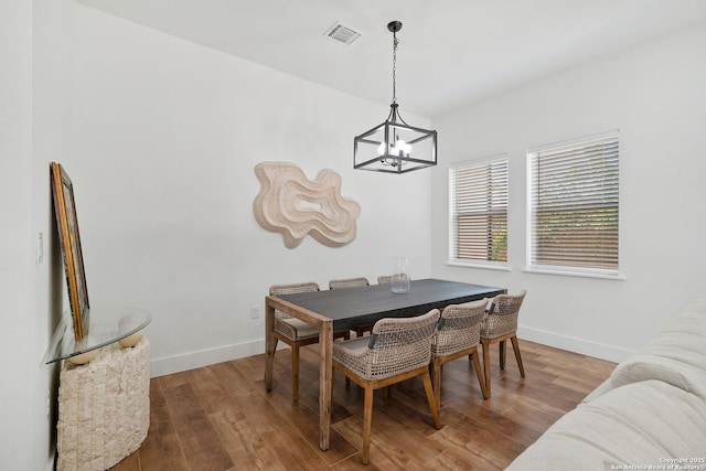 dining space with wood-type flooring and a notable chandelier