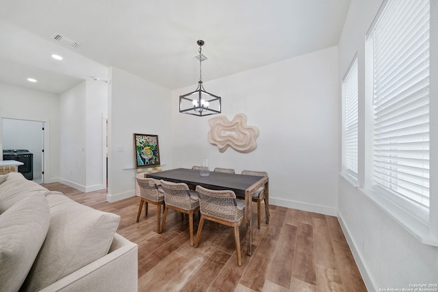 dining room featuring light wood-type flooring and an inviting chandelier