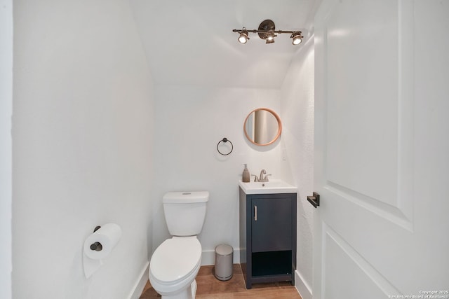 bathroom featuring hardwood / wood-style floors, vanity, lofted ceiling, and toilet