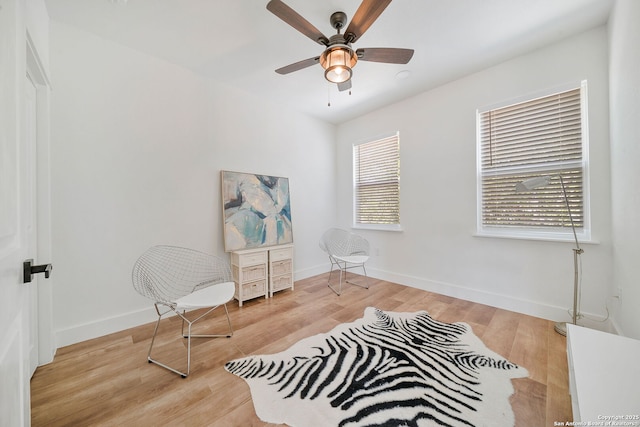 living area with light wood-type flooring, a wealth of natural light, and ceiling fan