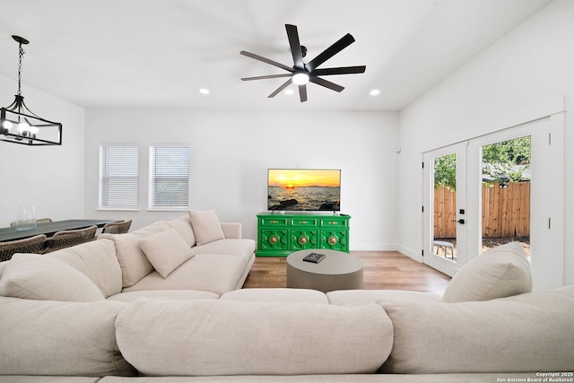 living room featuring ceiling fan with notable chandelier, light hardwood / wood-style flooring, and french doors