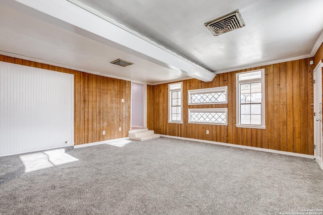 empty room with carpet, a healthy amount of sunlight, beamed ceiling, and wooden walls