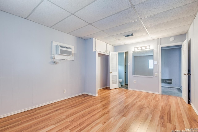 spare room featuring a paneled ceiling, light hardwood / wood-style floors, and a wall mounted AC