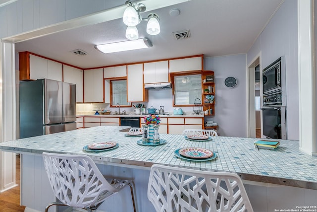 kitchen featuring kitchen peninsula, sink, white cabinetry, and black appliances