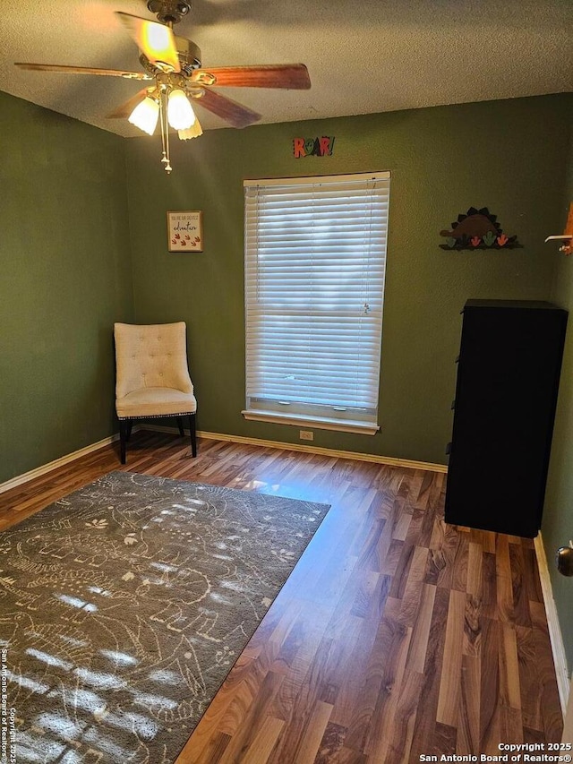 sitting room featuring a textured ceiling, ceiling fan, and dark wood-type flooring