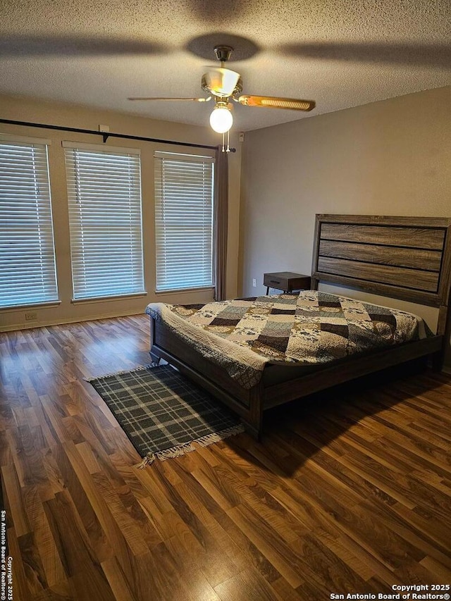 bedroom with ceiling fan, dark hardwood / wood-style flooring, and a textured ceiling