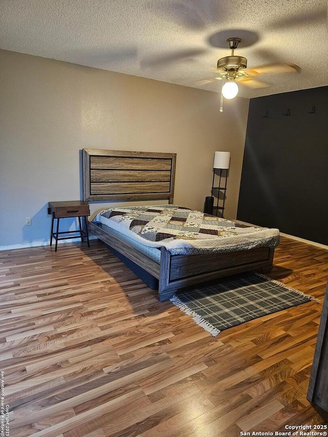 bedroom with ceiling fan, hardwood / wood-style floors, and a textured ceiling