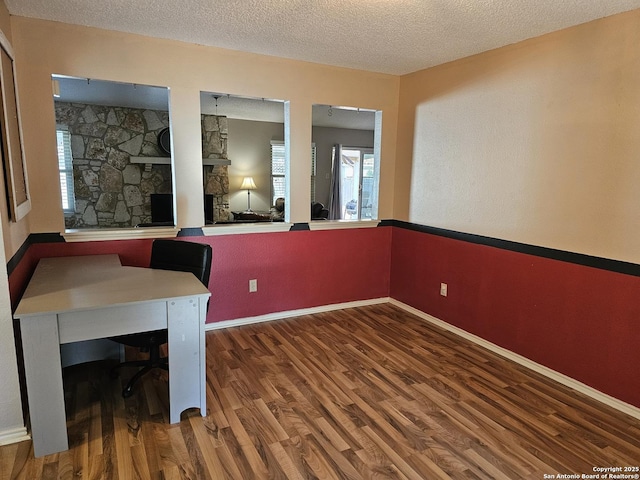 unfurnished office with a textured ceiling, dark hardwood / wood-style flooring, and a stone fireplace